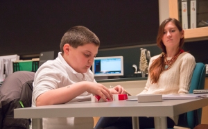 Vinnie Apicella, 9, of East Haven, demonstrates one of the testing procedures that participants would use for autism research while Whitney Hoffmann, graduate student watches on in the background.  Southern's Psychology Department has been performing autism research, centered on language difficulties, at one of their labs in Engleman Hall.