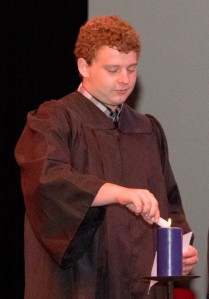 A student lighting a candle during the "Torch of Knowledge."